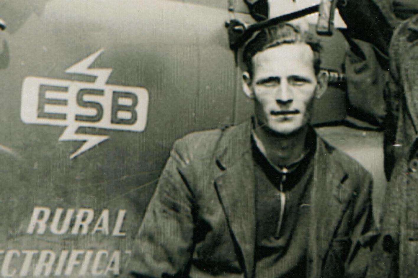 Tim Slevin, ESB engineer, seated beside an ESB vehicle marked with the ESB logo and the words “Rural Electrification”.