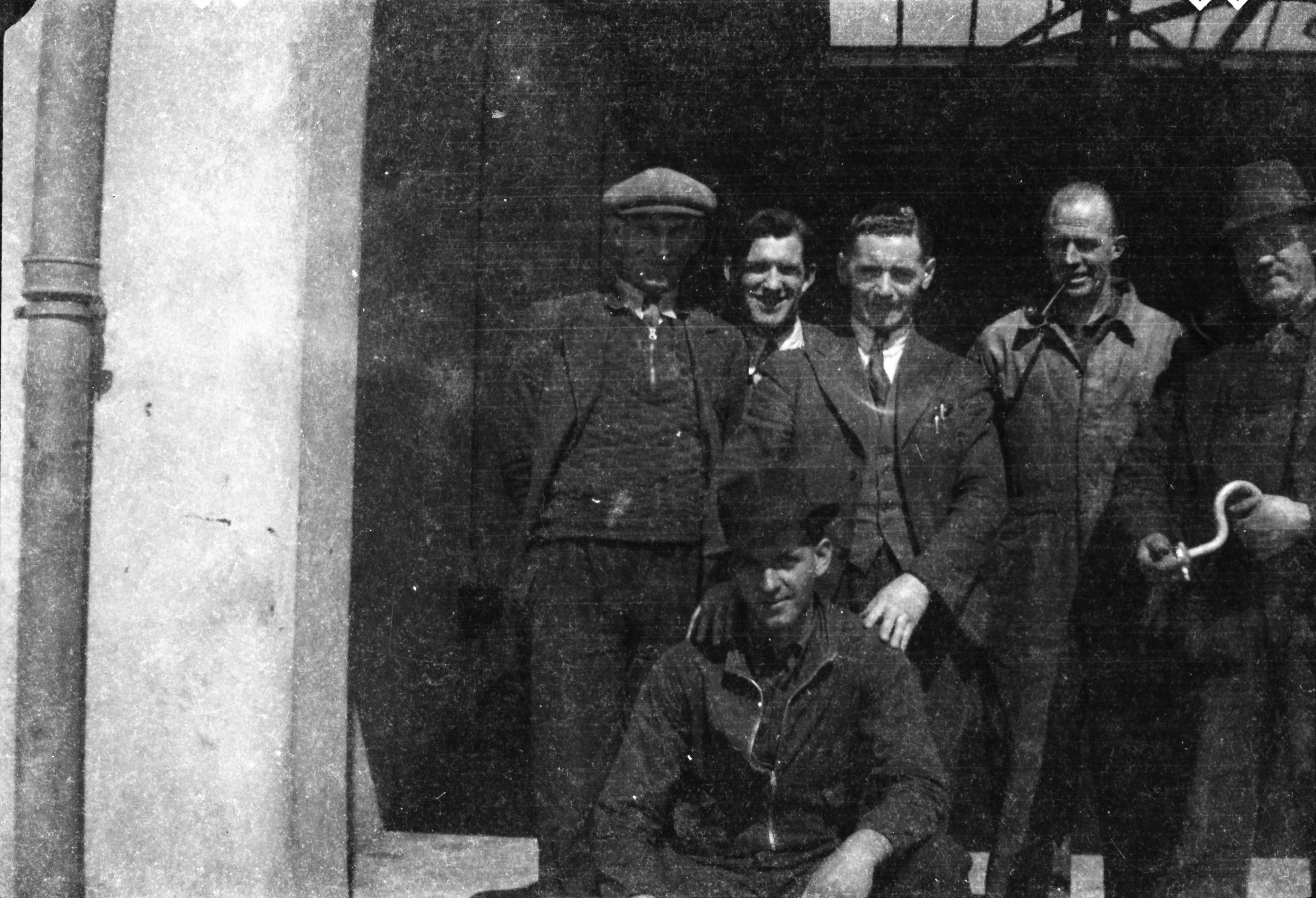 Black-and-white group photograph showing Jerry Corbett crouching in the foreground while five colleagues stand behind him at the entrance to a building.