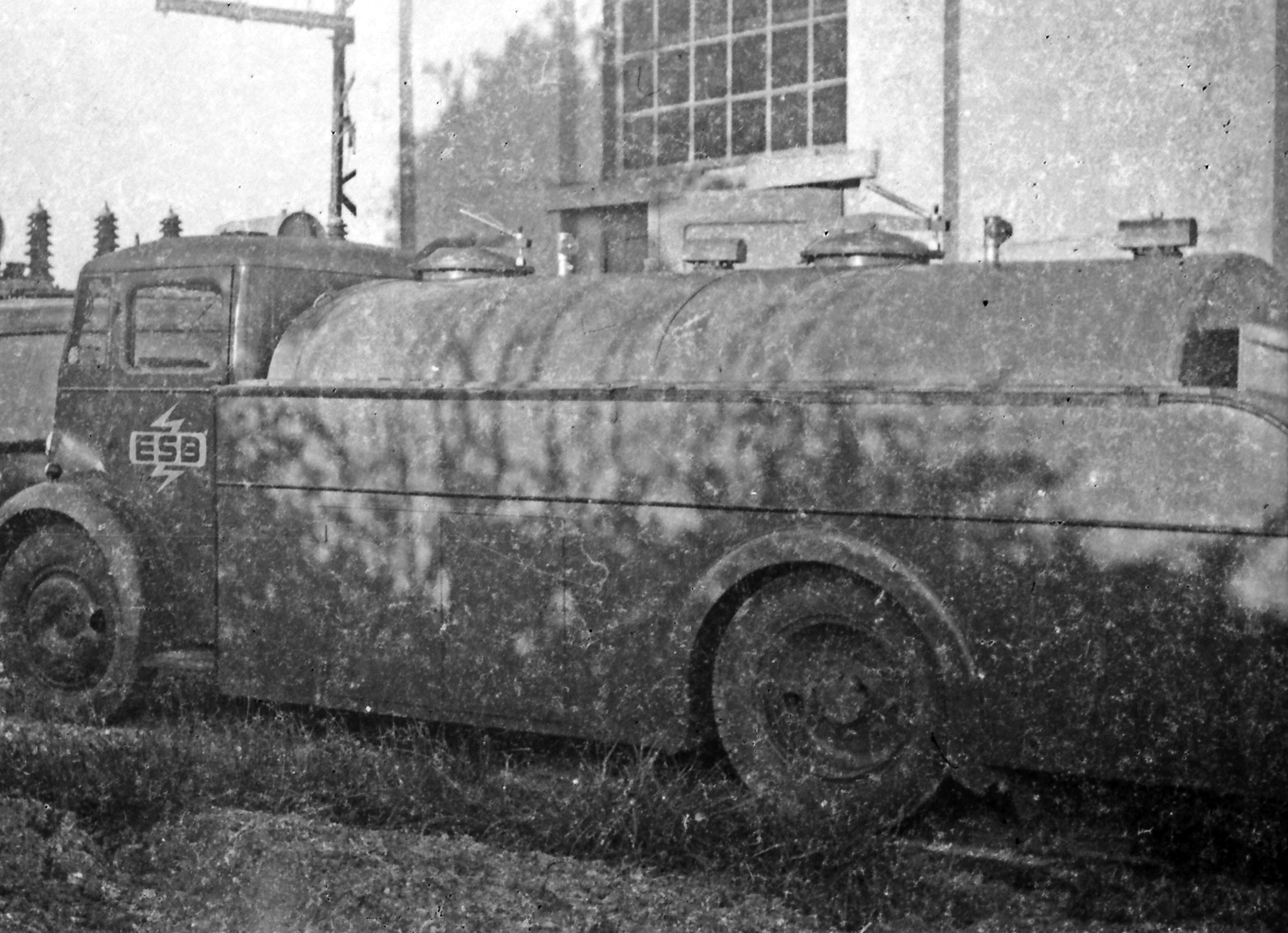 Black-and-white photograph showing an ESB fuel or utility tanker truck positioned outside an electricity facility, with electrical equipment visible in the background.