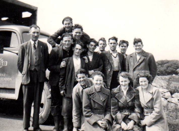 Group photograph of Tim Slevin, family members and ESB colleagues gathered beside an ESB vehicle, with a stone wall and open countryside in the background.