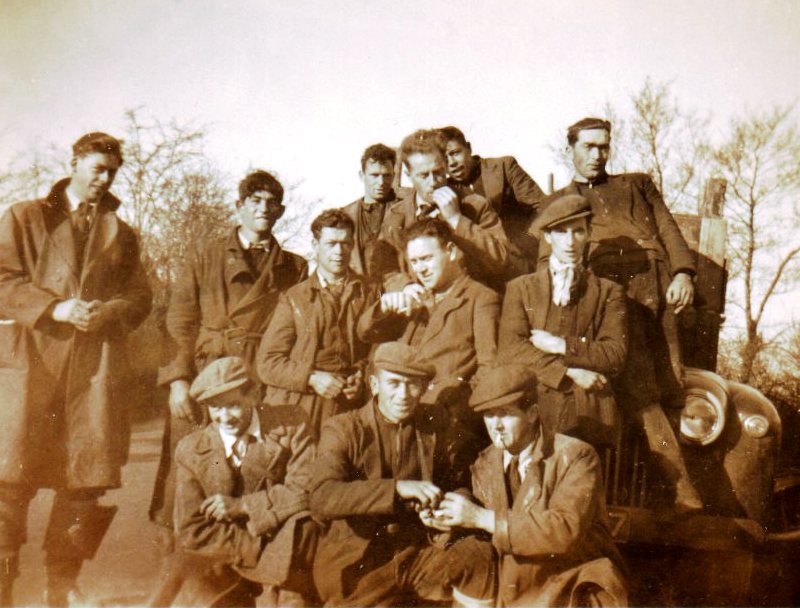 A group of rural electrification workers posing beside a vehicle on a rural road, with trees visible in the background.