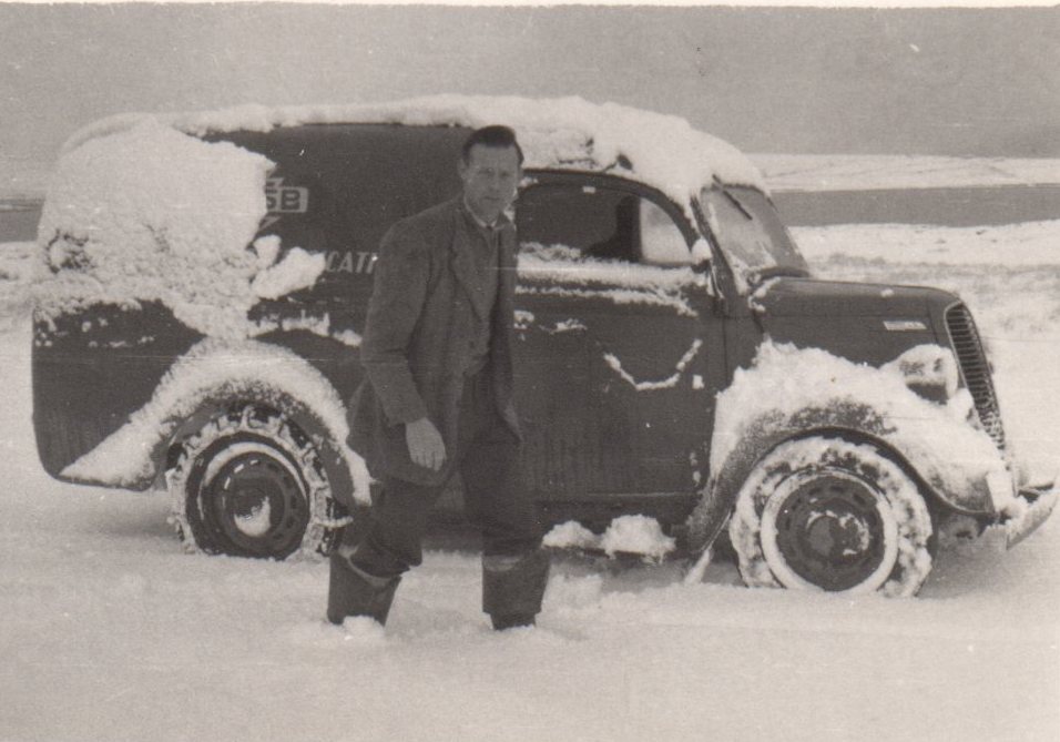 Tim Slevin standing in deep snow beside a snow-covered ESB vehicle in a rural landscape.