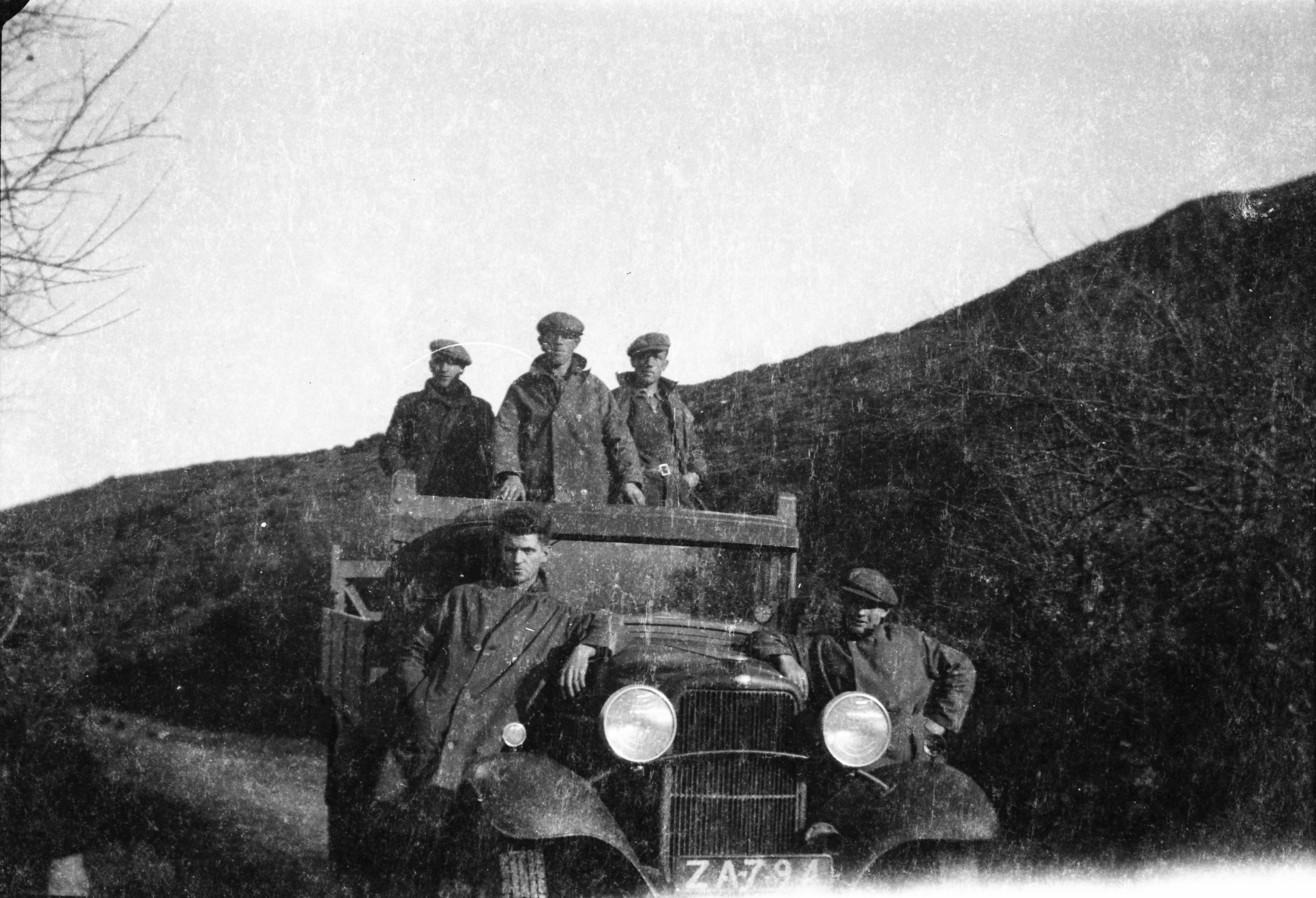 Black-and-white photograph showing Jerry Corbett and colleagues gathered around an ESB truck on a country road bordered by steep hillsides.