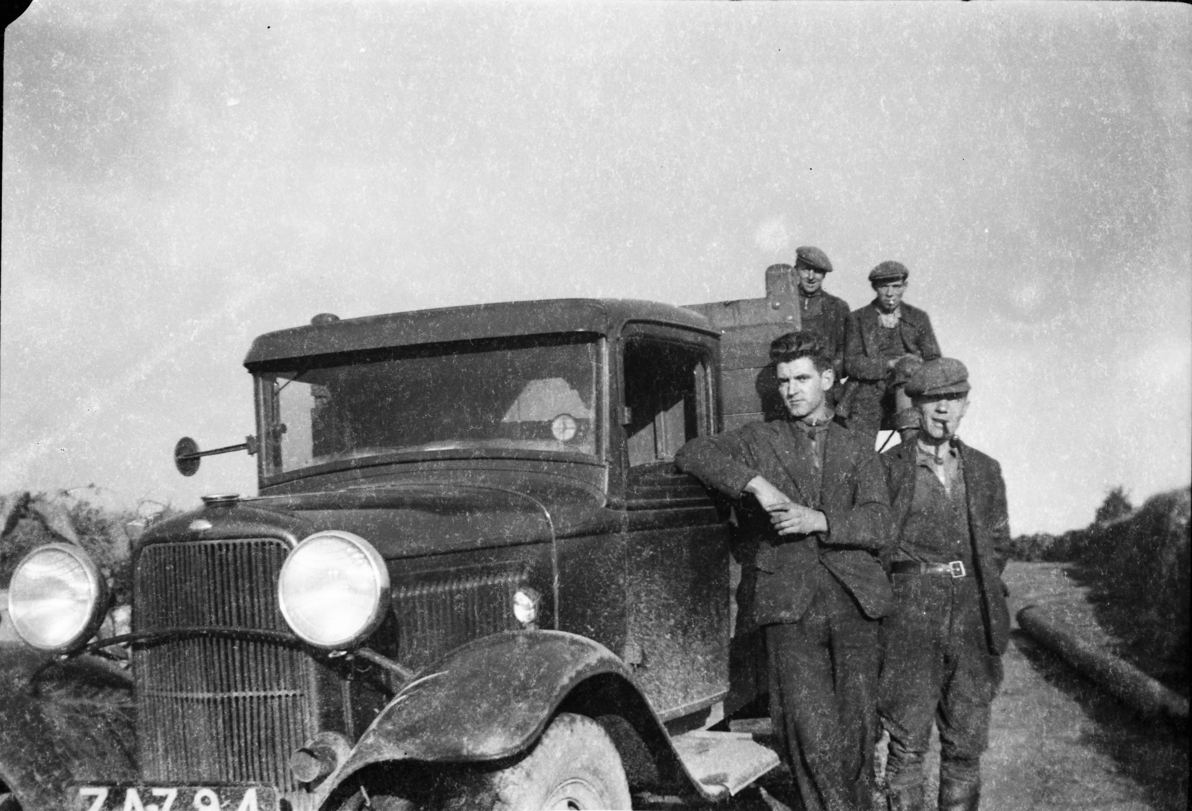 Jerry Corbett and three other colleagues posing with a mud-spattered ESB truck on a rural road, with a wooden electricity pole visible alongside the vehicle.