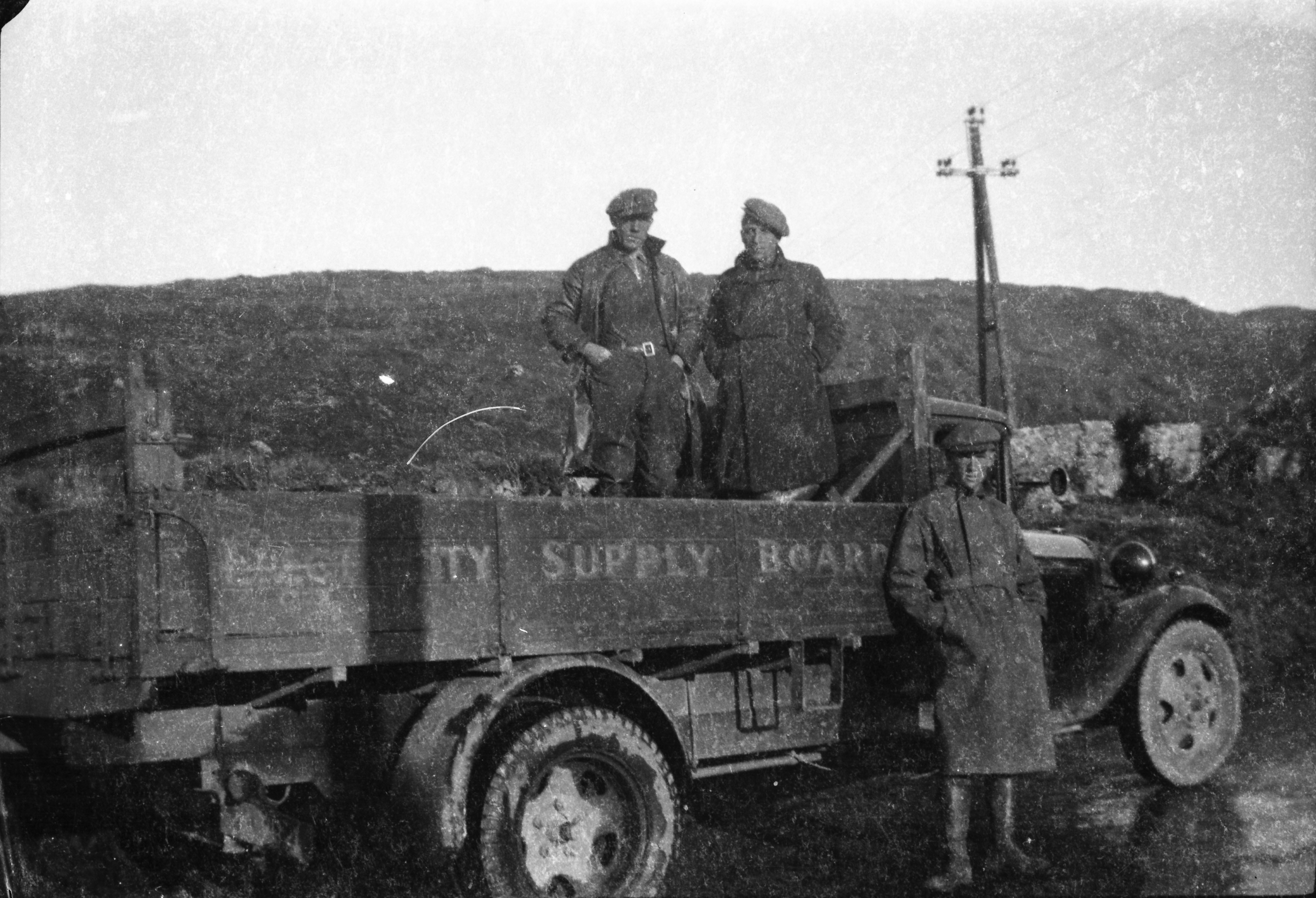 Early ESB flatbed truck parked on a rural roadside, with three workers posing for the camera and the words “Electricity Supply Board” visible on the side of the truck bed.