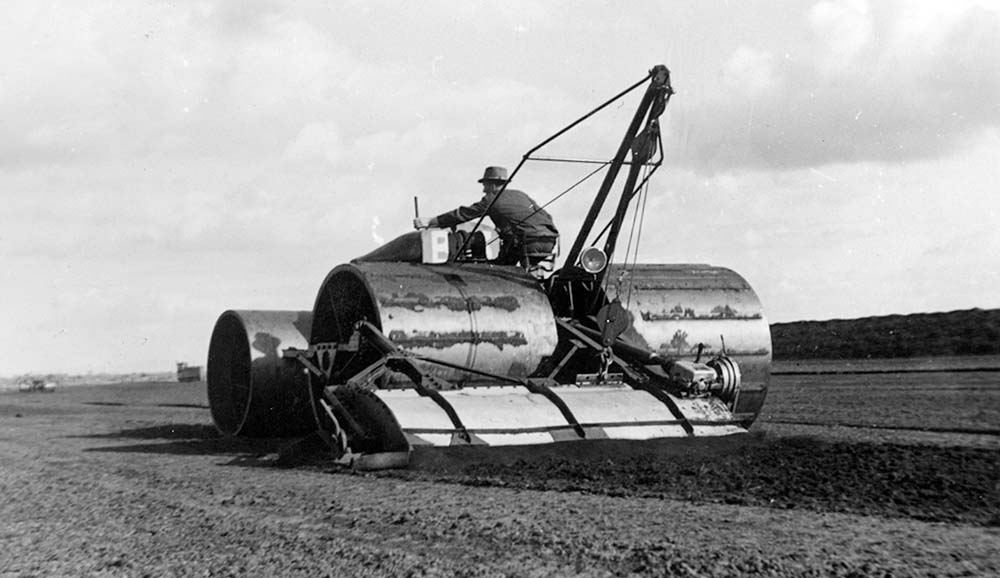 Operator using heavy machinery to process peat on a prepared bog.