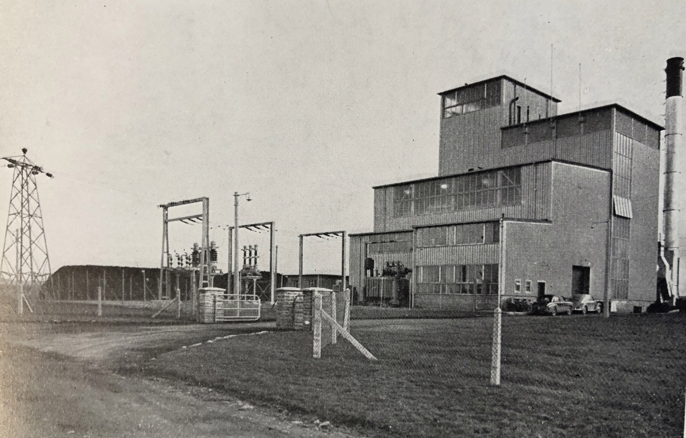 View of Miltown Malbay Generating Station with station buildings, chimney and electricity infrastructure in the foreground.