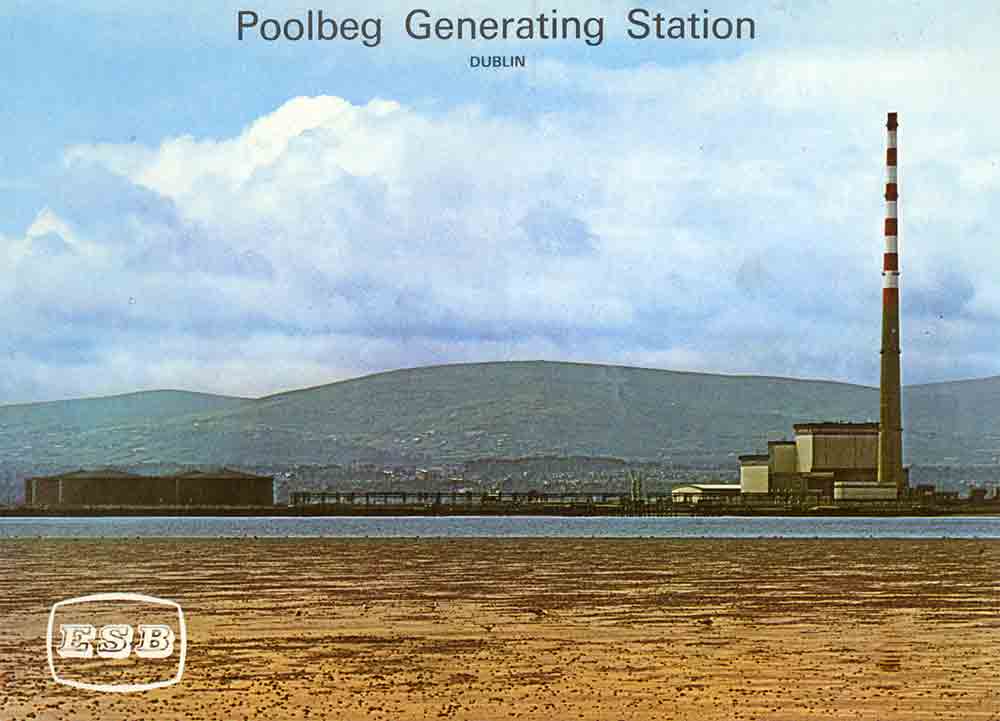 View of Poolbeg Generating Station across Dublin Bay, showing the station buildings and chimney with the Dublin Mountains in the background.