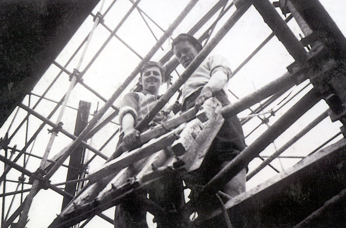 Construction workers standing on scaffolding during the construction of Rhode Generating Station.