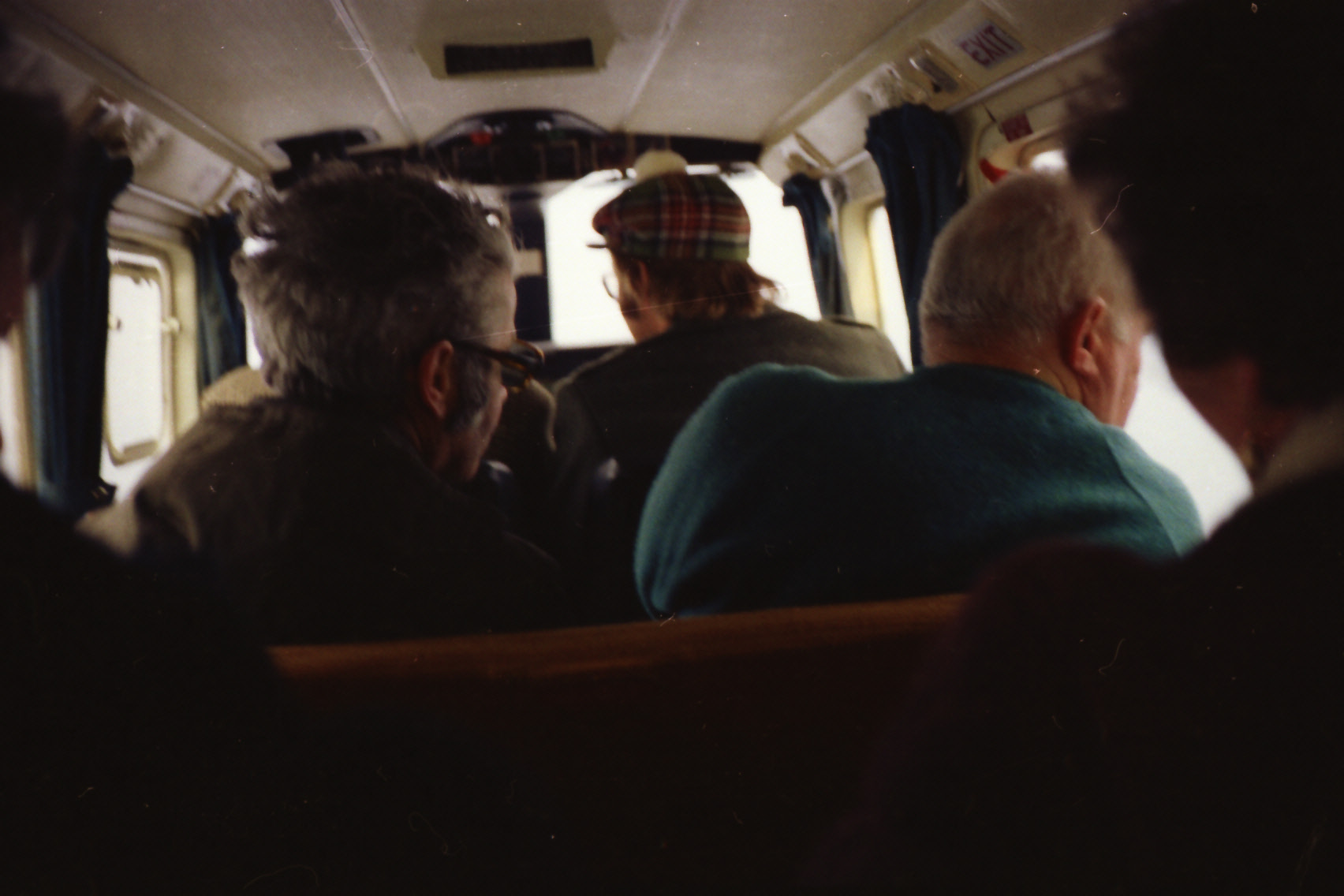 Colour photograph taken from the rear of a small aircraft cabin, showing passengers seated during travel connected with the electrification of Ireland's offshore islands in the early 1970s.