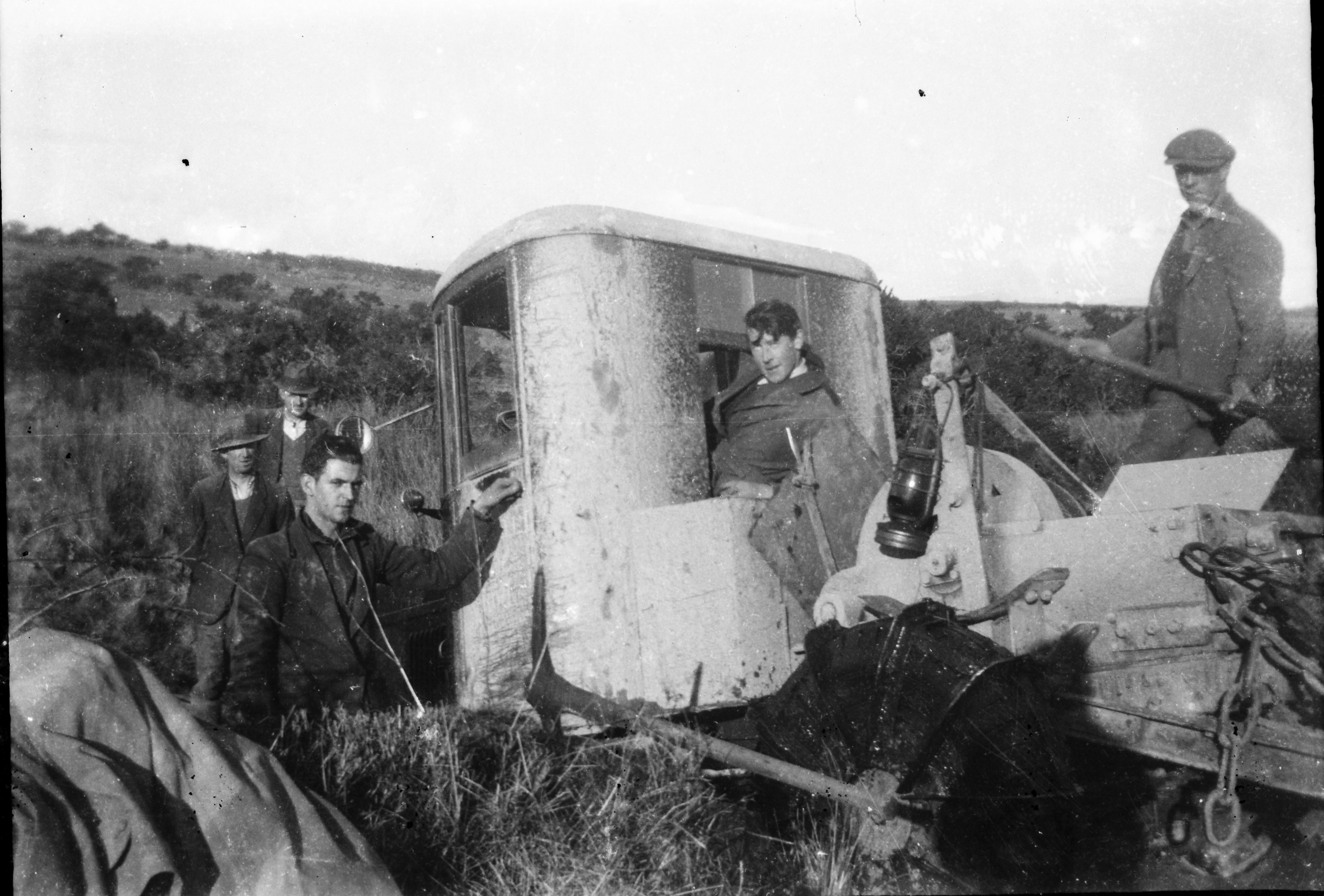 Black-and-white photograph showing Rural Electrification Scheme workers beside a tracked excavator or trenching machine used for construction work in a rural landscape.