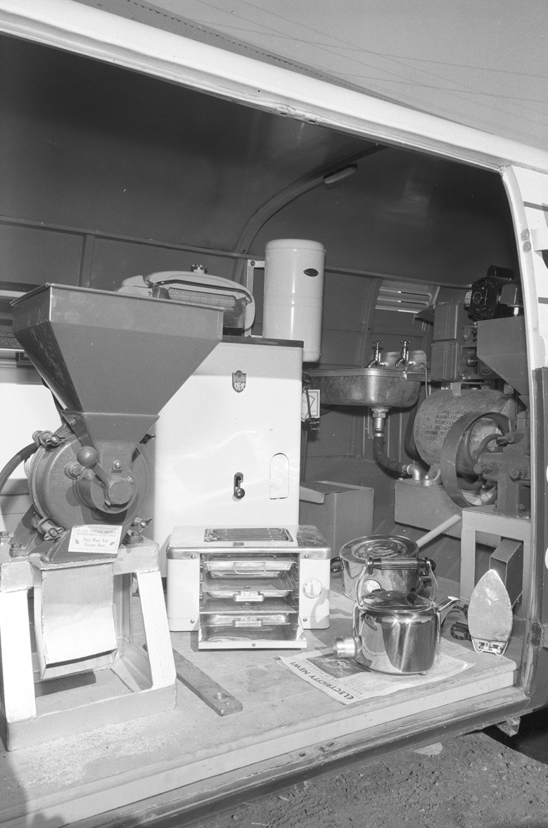 Black-and-white photograph showing electrical appliances and farm equipment displayed inside an ESB demonstration vehicle.