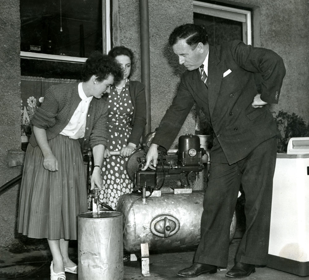 A man demonstrating an electric boiler to two women